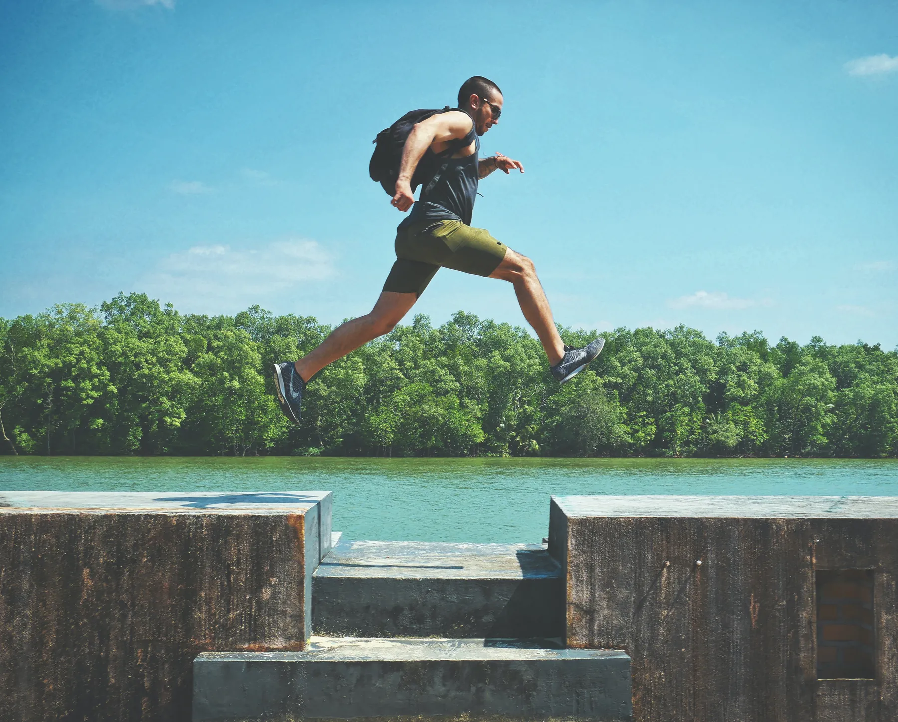 A man leaping between stone ledges by a river